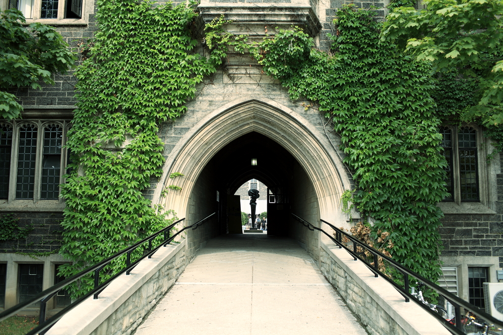 Picture of a gateway in building in the Gothic Revival style. It is covered in ivy.